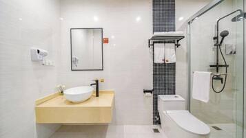 A modern bathroom with a white sink, black faucet, and a glass shower enclosure.
