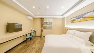 Una habitación de hotel con cama, televisión, escritorio y ventana con cortinas.