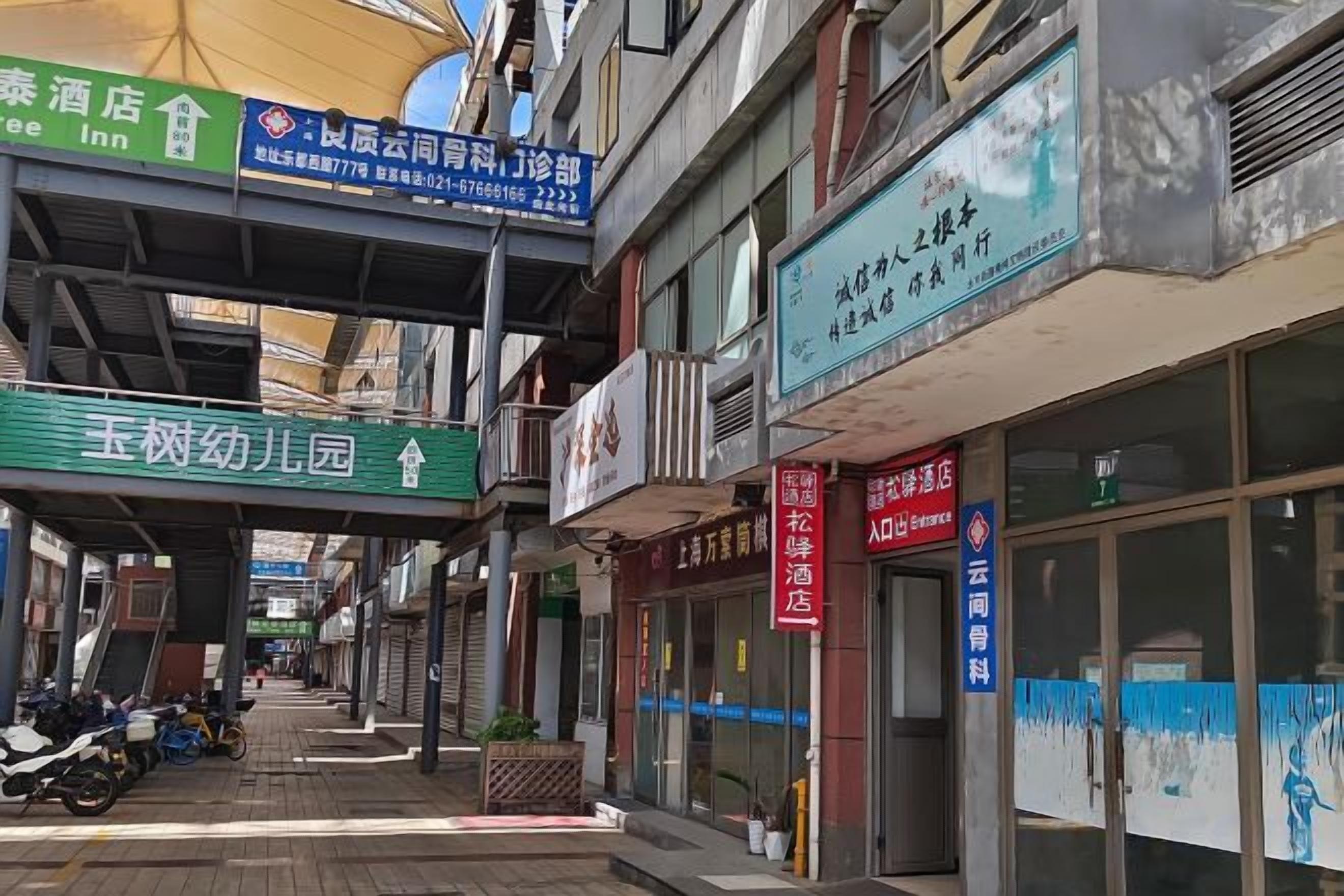 A street view with various storefronts, including a hotel, a restaurant, and a shop with a blue sign.