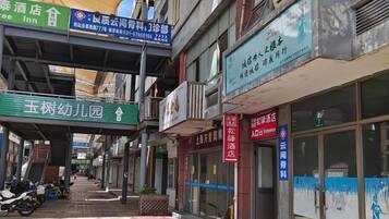 A street view with various storefronts, including a hotel, a restaurant, and a shop with a blue sign.