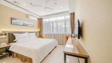 A hotel room with a bed, bedside table, lamp, TV, and a large window with curtains.