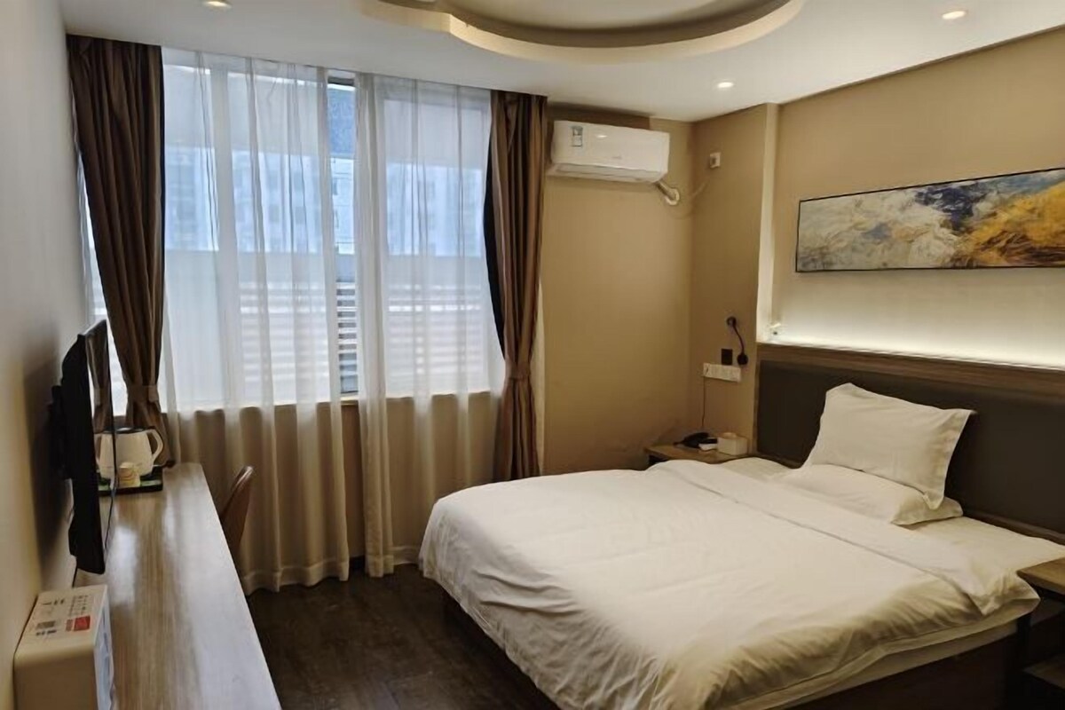 Una camera d'albergo con un letto, una scrivania, una sedia, un condizionatore d'aria e un quadro appeso al muro.