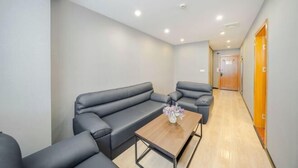 A modern living room with a sofa set, a wooden coffee table, and a vase of flowers. - Songyi Hotel Songjiang University Town Rongfeng Life Square Branch (Shanghai)
