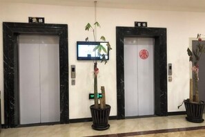 Three elevators with digital displays, a potted plant, and a red seal on one door. - Songyi Hotel Songjiang University Town Rongfeng Life Square Branch (Shanghai)