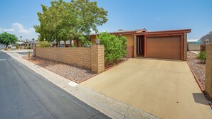 A residential driveway leading to a garage, surrounded by a brick wall and a small garden area. - Swim & Golf: Palm Desert Home in Senior Community! (Palm Desert)