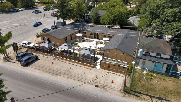 An aerial view of a hotel with a patio area, outdoor seating, and a parking lot. - 30 seconds to the beach.Family sized 2 bedroom suites (Wasaga Beach)