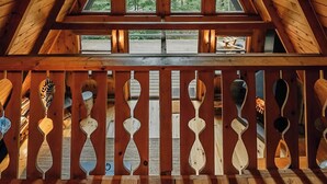 Une cabane en bois avec un toit triangulaire et un balcon agrémenté de balustrades décoratives.