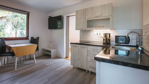 Una cocina moderna con una mesa y sillas de madera, un microondas empotrado y un televisor montado en la pared.