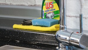Un lavamanos de cocina con una botella de jabón para platos W5 Power Green, una esponja amarilla y un grifo.