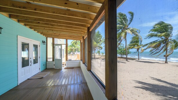 Une terrasse en bois offrant une vue sur une plage et des palmiers.