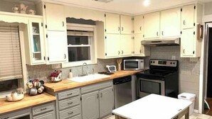 A kitchen with grey cabinets, a microwave, a stove, and a sink.