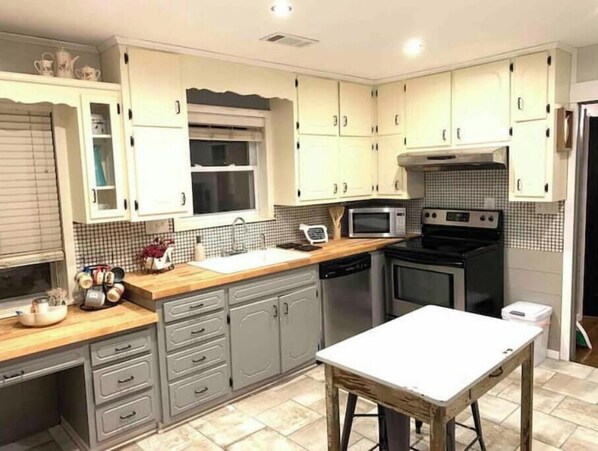 A kitchen with grey cabinets, a microwave, a stove, and a sink.
