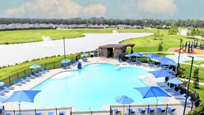 A swimming pool with lounge chairs and umbrellas, surrounded by a fence and a pavilion. - Modern 3br/2ba with 3 king beds · Pool · Pets OK! (Patton Village)