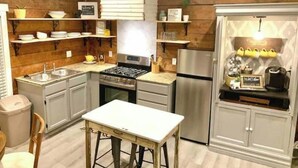 A compact kitchen with wooden paneling, stainless steel appliances, and a small dining area.