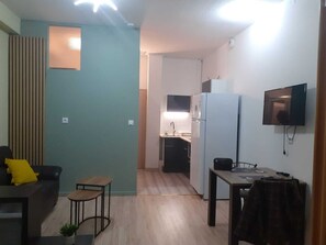 A compact living space with a kitchenette, a dining area, and a seating area with a sofa and a small table.
