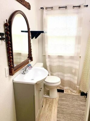 A bathroom with a wooden-framed mirror, a white sink, and a toilet.