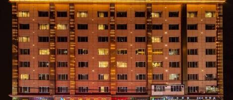 A multi-story hotel with a row of shops on the ground floor.
