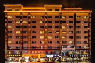 Un hotel de varios pisos con una fila de tiendas en la planta baja.