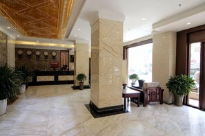 A hotel lobby with marble flooring, a reception desk, and potted plants. - Lanzhou Xindeli Hotel (Lanzhou)