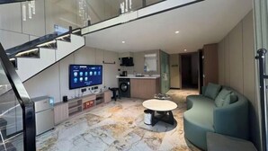 Ein modernes Interieur mit Treppe, Flachbildfernseher, Küchenzeile und einer Sitzecke mit rundem Tisch.
