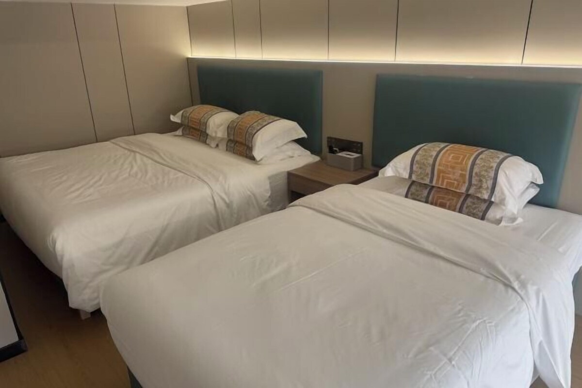 A hotel room with two beds, each with a headboard and a bedside table.