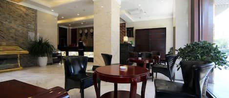 Un vestíbulo de hotel con asientos de cuero, una recepción y un ventanal grande.