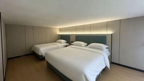 Ein Hotelzimmer mit zwei Betten, einem Kopfteil und einer Wandleuchte.