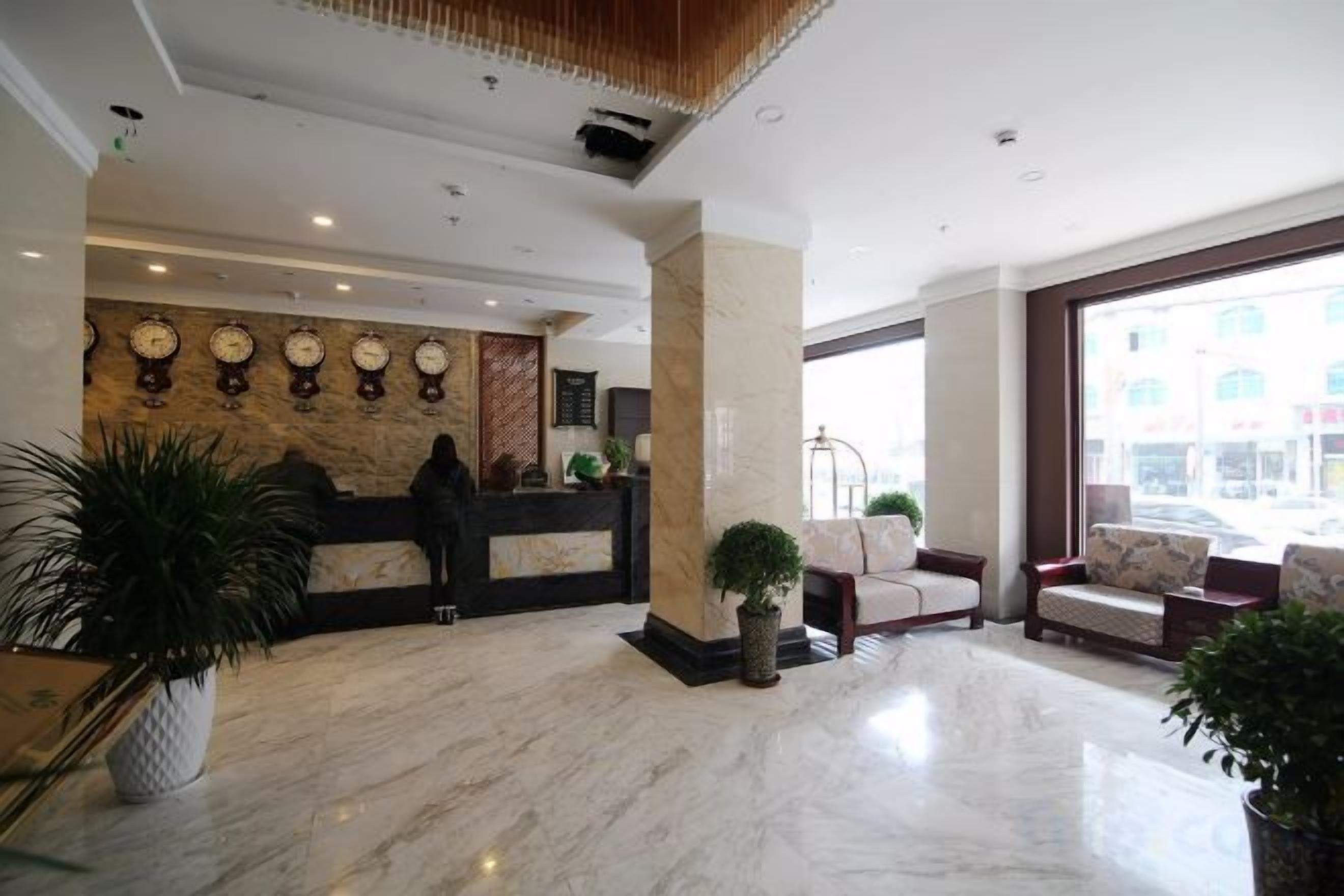 A hotel lobby with a reception desk, seating area, and large windows.