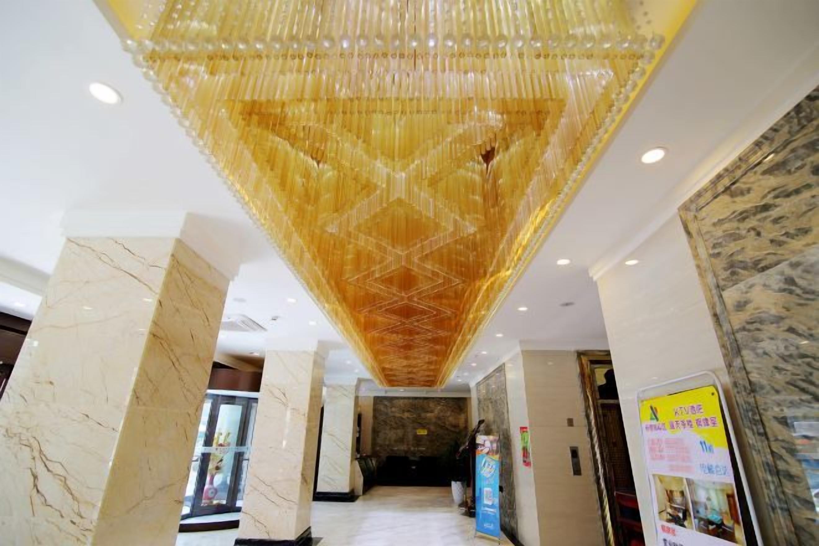 A hotel lobby with a large chandelier, marble columns, and a reception desk.