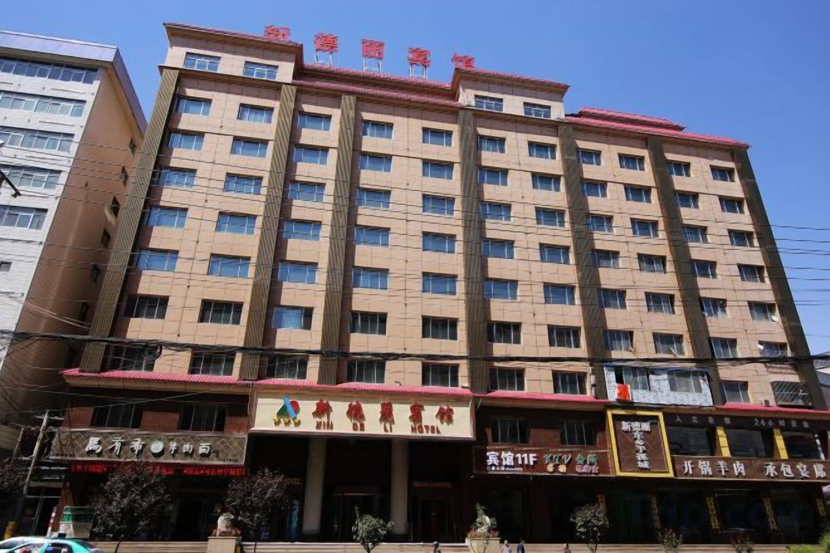 A multi-story hotel with a uniform facade, multiple balconies, and several ground-level shops.
