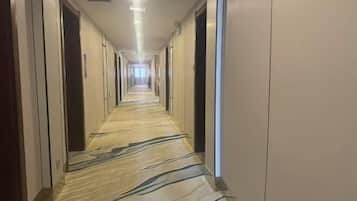 A long, narrow hotel corridor with doors on both sides and a patterned carpet.