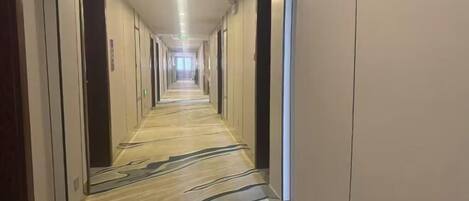 A long, narrow hotel corridor with doors on both sides and a patterned carpet.