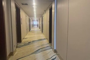 A long, narrow hotel corridor with doors on both sides and a patterned carpet. - Lanzhou Xindeli Hotel (Lanzhou)