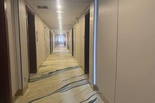 A long, narrow hotel corridor with doors on both sides and a patterned carpet.