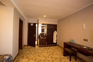 A hotel room with a bed, a desk, a wardrobe, and a bathroom visible through an open door. - Lanzhou Xindeli Hotel (Lanzhou)
