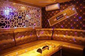 A leather sofa with a tray table, a decorative wall with a geometric pattern, and an air conditioning unit. - Lanzhou Xindeli Hotel (Lanzhou)