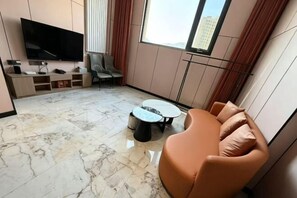 A modern living room with a flat-screen TV, a sofa, a coffee table, and a dining table.