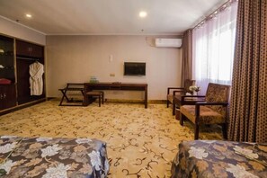 A hotel room with a patterned carpet, a desk with two chairs, a television, and a wardrobe. - Lanzhou Xindeli Hotel (Lanzhou)