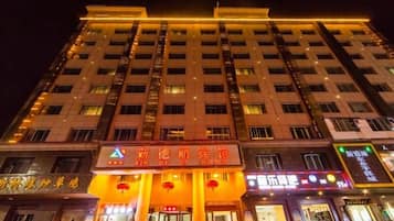 Hotel de varios pisos con letreros iluminados y varias tiendas a nivel de calle.