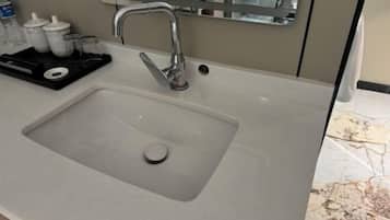 A bathroom sink with a modern faucet, a mirror above it, and toiletries on a tray.