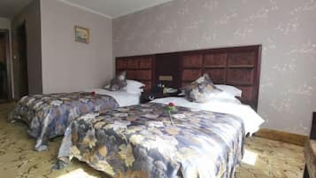 A hotel room with two beds, floral bedspreads, a wooden headboard, and a patterned carpet.