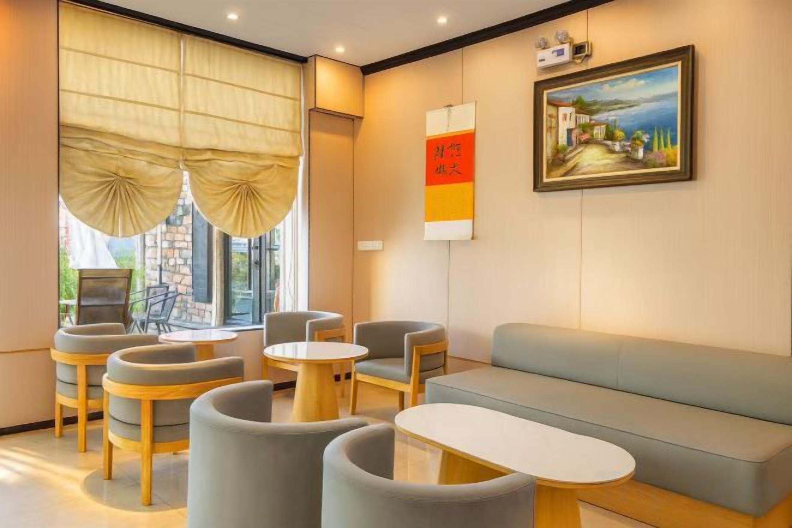 A hotel lobby with a sofa, chairs, a table, and a painting on the wall.