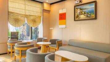 A hotel lobby with a sofa, chairs, a table, and a painting on the wall.