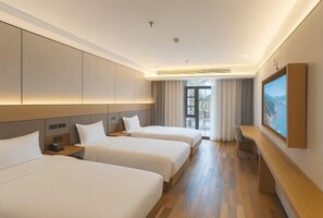 Une chambre d’hôtel avec deux lits, un bureau, une télévision et une grande fenêtre.