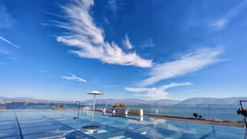 Una piscina de borde infinito con fondo de cristal que ofrece vistas claras a las montañas y al agua.