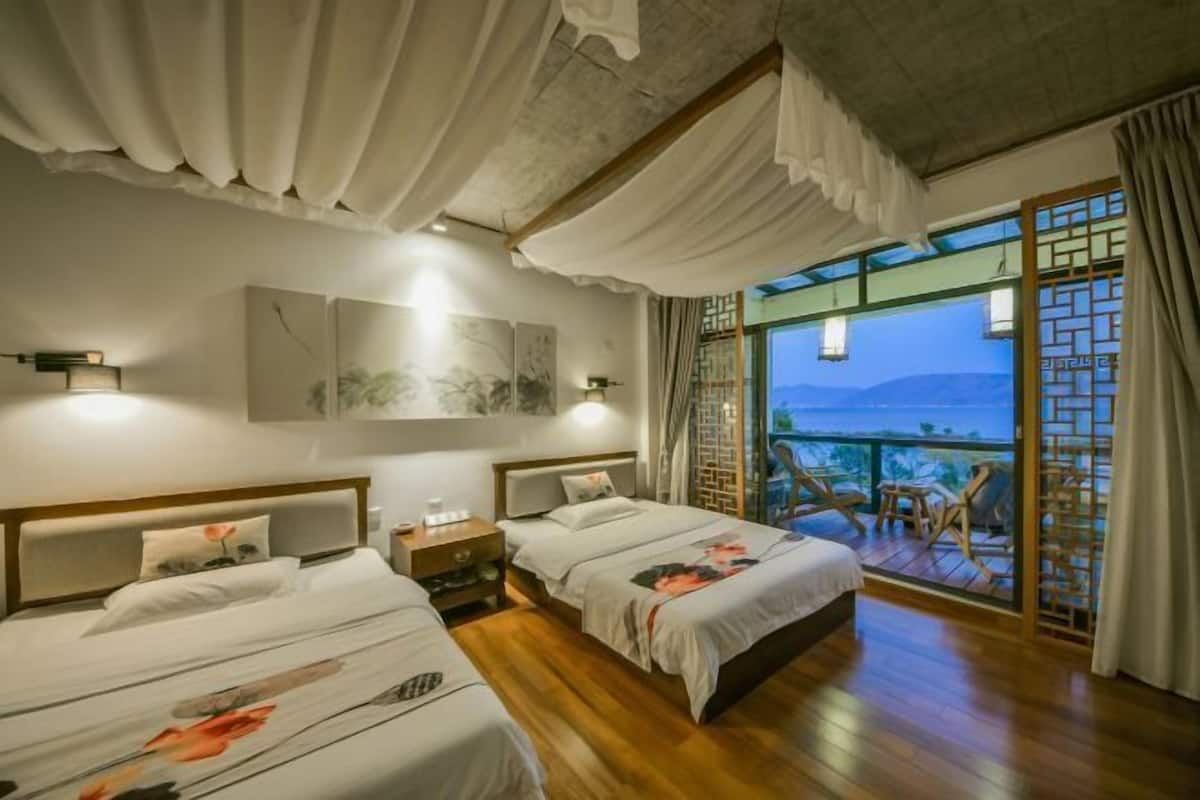 A hotel room with two beds, wooden flooring, a balcony with a view, and traditional decor.