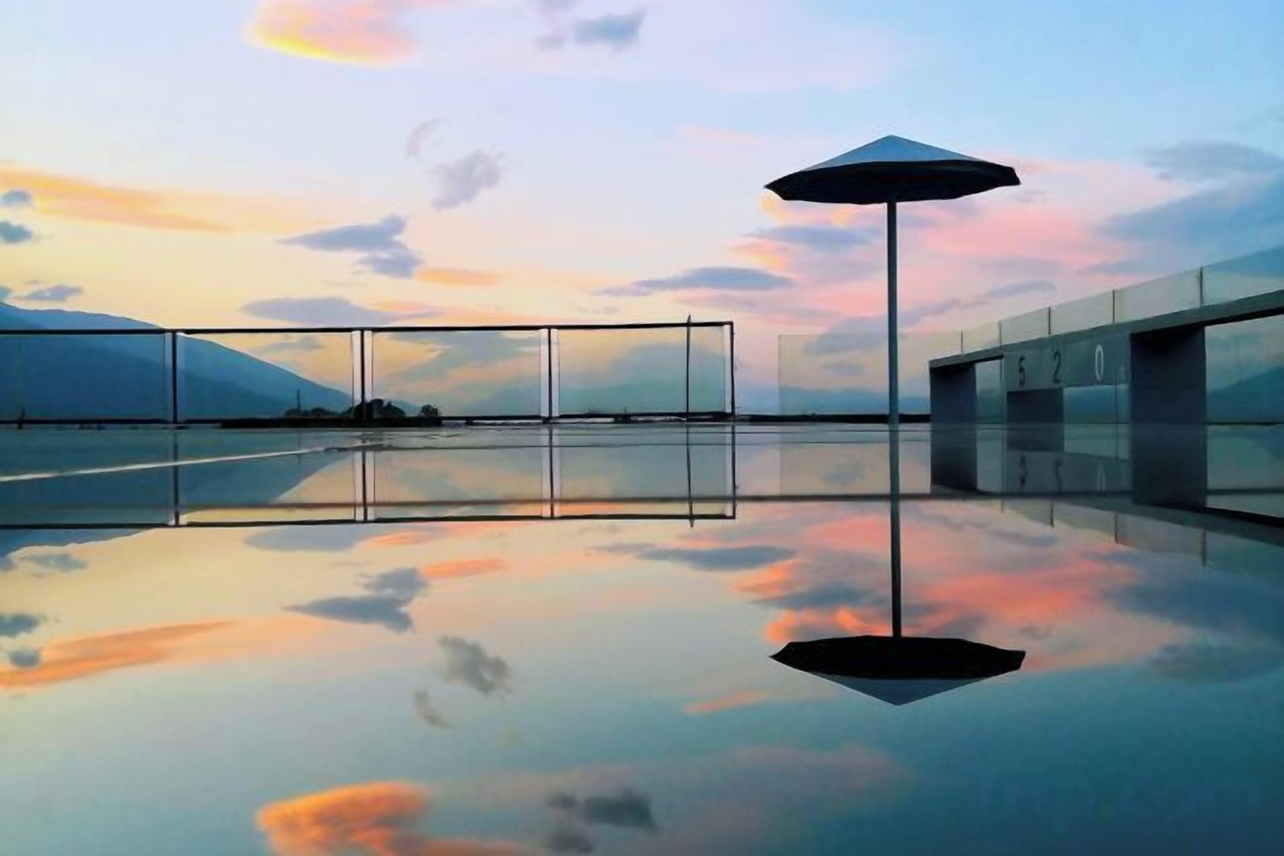 Un estanque reflectante con un edificio moderno y un cielo despejado.