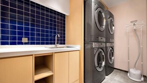 Een wasserette met een wasmachine en droger, een gootsteen en een tuinslanghaspel.