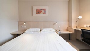 Een hotelkamer met een bed, nachtkastjes, een bureau en een stoel.