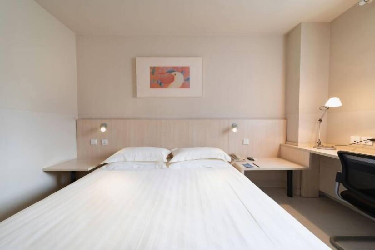 Ein Hotelzimmer mit Bett, Nachttischen, Schreibtisch und Stuhl.